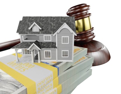 Miniature house with stack of money and wooden gavel isolated on a white background