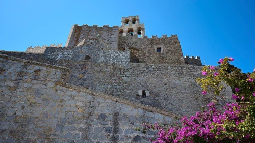 Historic castle walls with blooming flowers and clear blue sky, Agiou Theologou Monastery, St