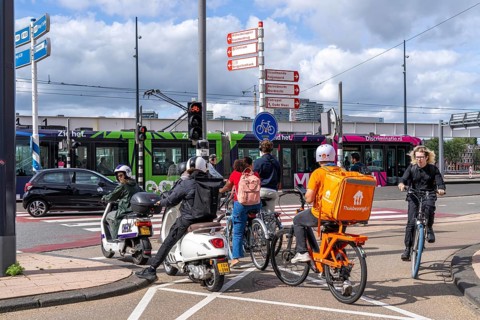 Cyclist, moped rider, waiting at a red traffic light, Feijenoord, in front of the Erasmus Bridge,