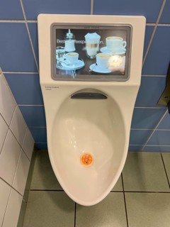 Toilet in a service station, on a motorway, gents, urinal with built-in video monitor, shows