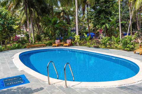 Swimming pool in tropical resort with small garden
