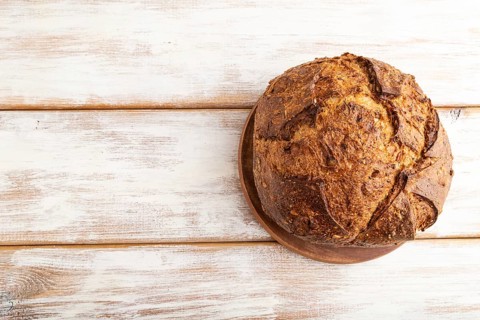 Fresh homemade golden grain bread with wheat and rye on white wooden background. top view, flat