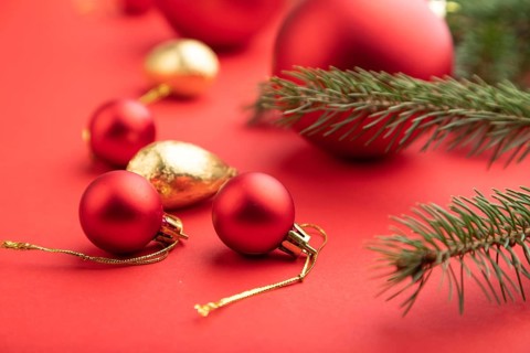 Christmas or New Year composition. Decorations, red balls, fir and spruce branches, on a red paper