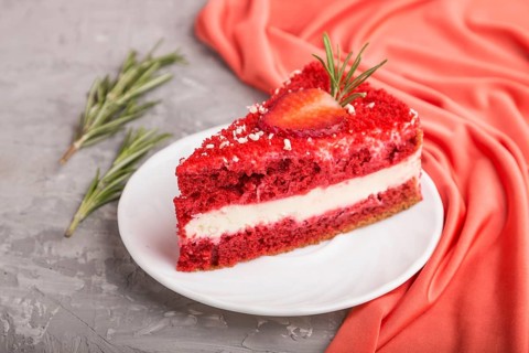 Homemade red velvet cake with milk cream and strawberry on a gray concrete background with red