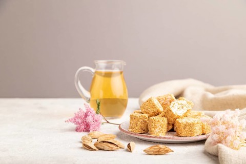 Traditional turkish delight (rahat lokum) with glass of green tea on a gray concrete background and
