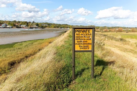 Private No Access sign of River Deben flood defence wall, Suffolk, England, UK view upstream