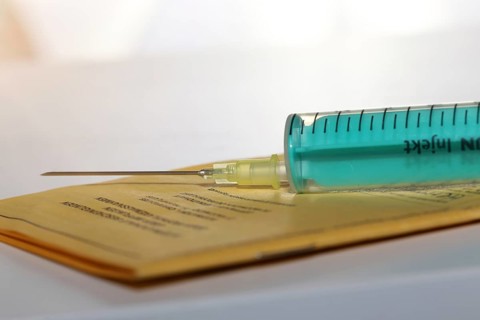 Symbolic image of vaccine with vaccination card and syringe
