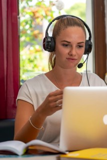 Young student learns at home, online, in conversation with other students