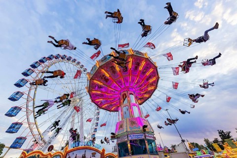 Chain carousel and Ferris wheel in the evening. 177th Cannstatter Volksfest at the Cannstatter