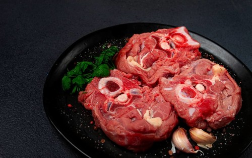 Raw steak, calf's neck on the bone, fresh meat, on a black plate, top view, no people