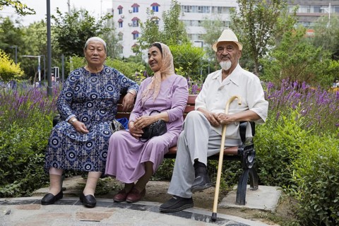 Three elderly Uyghurs sitting on a park bench in the city Hami, Kumul, one of China's ethnic