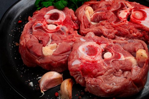Raw steak, calf's neck on the bone, fresh meat, on a black plate, top view, no people