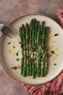 Grilled asparagus, spices and herbs, parmesan cheese, on a beige plate, top view, rustic, no people