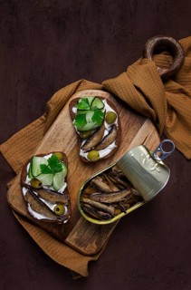 Sandwiches, black bread with sprats, cream cheese, cucumbers, on a cutting board, top view,