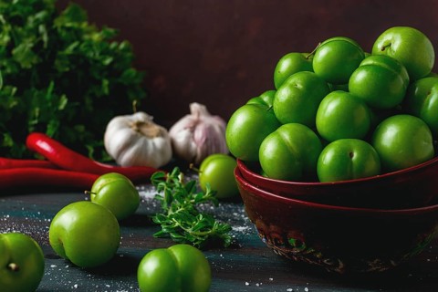 Tkemali, green cherry plum, with ingredients for sauce, cilantro, mint, hot pepper, garlic, on a