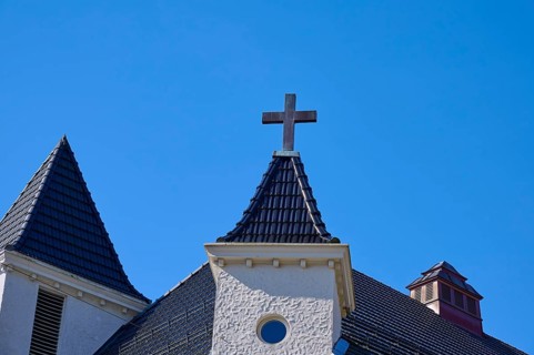 Church towers with cross and roof in front of a clear blue sky, Bryggen, Bergen, Vestland, Norway,
