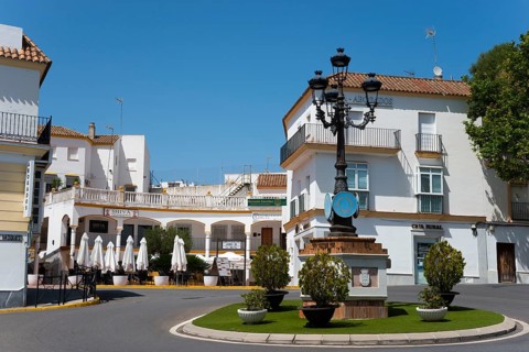 Inviting square with cafés and typical white houses, crowned by a decorative street lamp, Arcos de