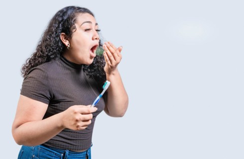 Young woman holding brush with bad breath isolated. Person with brush and bad breath isolated,
