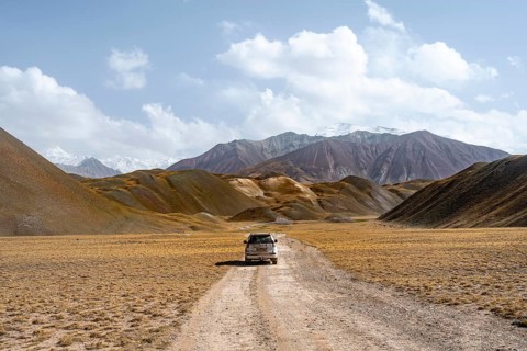 Nature tourism, road trip, overlander, off-road vehicle on a gravel road in the Pamir Mountains,
