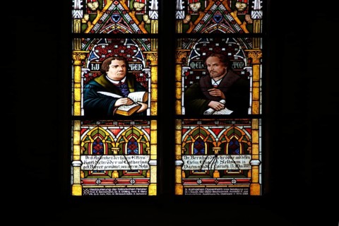 Colourful stained glass window with reformers Martin Luther with quill and Bible and Philipp