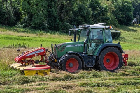 A Fendt 312 Vario tractor with Pöttinger mower mowing a meadow, Hegau, Baden-Württemberg, Germany,