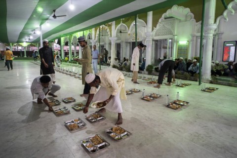 Volunteers distribute and arrange rows of 'iftar' meal for devotees to break their fast, during the