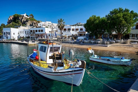 Two fishing boats moored at a harbour quay on a Greek island, surrounded by clear water and