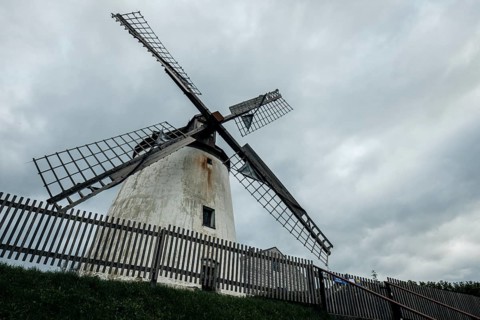 Large historic windmill under a cloudy sky, wooden fence, Podersdorf, Burgenland, Austria, Europe