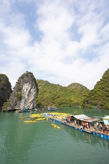Holidaymakers queue for a kayak on a jetty, behind the karst rocks in Lan Ha Bay, Halong Bay,