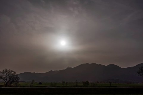 Sahara dust covers the sun in front of a mountain landscape, spring, Loisach-Lake Kochel-Moore,
