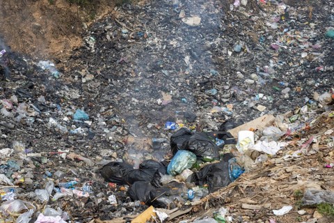 Coking rubbish dump, rubbish pit with waste and plastic rubbish, karst landscape near Vang Vieng,