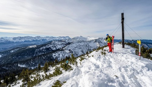 Ski tourer at the summit of the Simetsberg with summit cross, mountain panorama, Estergebirge,