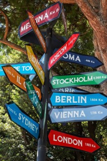 Close-up of signpost with colourful arrow markers indicating distances in kilometres to various