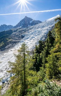 View of glacier Glacier des Bossons with sun star, behind summit of Aiguille du Midi, Chamonix,