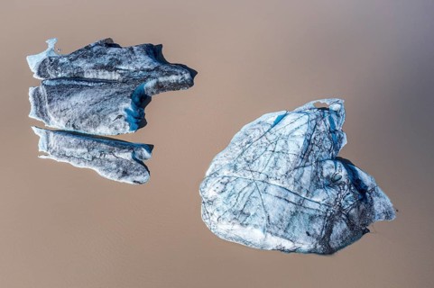 Glacier tongue of the Öræfajökull, small icebergs melting in the lagoon, muddy water, top down