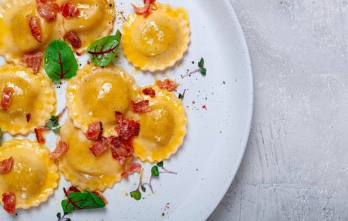 Fresh ravioli, with butter, spices and herbs, fried bacon, on the table, top view, light