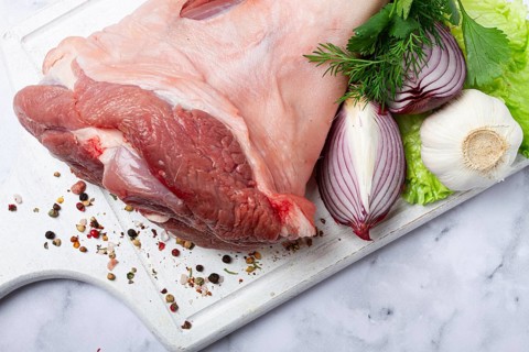Raw pork knuckle, on a wooden chopping board, with spices, close-up, top view, no people