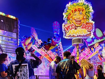 People in front of the illuminated carousel Voodoo Jumper at night, Cranger Kirmes, Herne, Ruhr