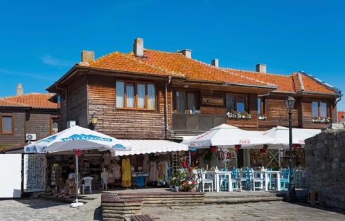 Restaurant with open-air tables next to souvenir shops in a traditional wooden building, Black Sea,