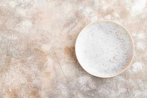 Empty blue and gold ceramic plate on brown concrete background. Top view, copy space, flat lay