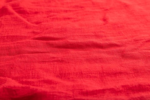 Fragment of smooth red linen tissue. Top view, flat lay, natural textile background and texture