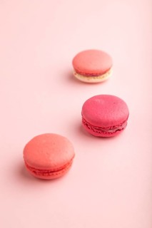 Purple and pink macaroons on pink pastel background. side view, close up, still life, selective