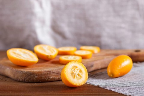 Sliced kumquats on a wooden kitchen board, close up, selective focus, copy space