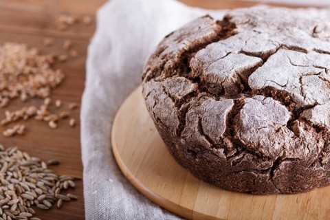 Yeast free homemade bread with whole rye and wheat grains on rustic wooden background. close up
