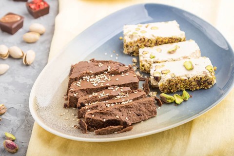 Traditional arabic sweets sesame halva with chocolate and pistachio and a cup of coffee on a gray