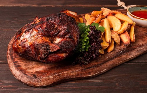 Pork knuckle, in soy-honey sauce, with fried potatoes, on a wooden chopping board, homemade, no
