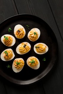 Boiled eggs stuffed with yolk with mayonnaise, on a black plate, selective focus, blurry, close-up,