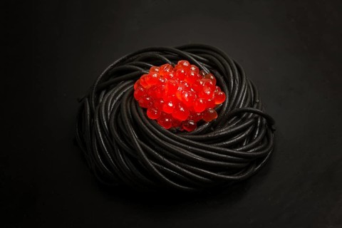 Black spaghetti with red caviar, pasta, on a black background, top view, no people