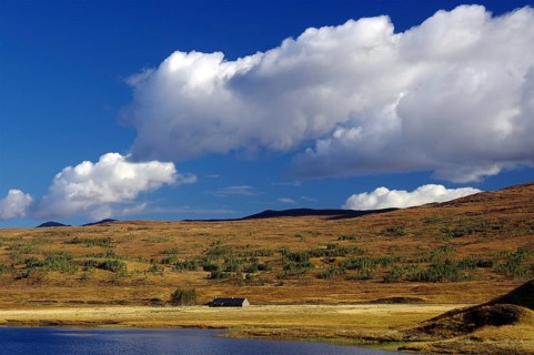Gentle hills and wide grassland under a clear blue sky with white clouds, autumn, October,
