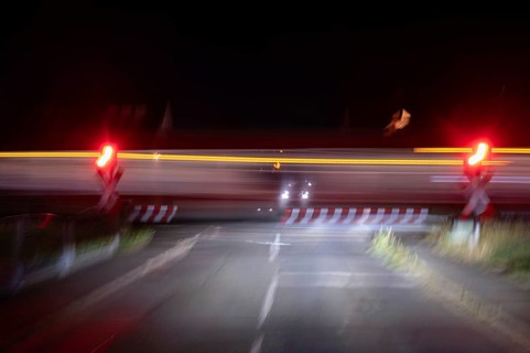 Passing train at a level crossing with barriers at night, Eckental, Middle Franconia, Bavaria,